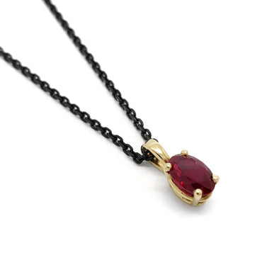 10kt yellow gold pendant with oval lab-grown ruby on a black chain, close-up view