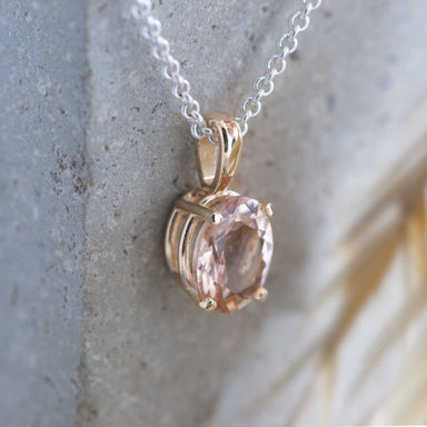 10kt yellow gold pendant with oval peach morganite on a silver chain, shown against stone
