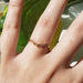 14k rose gold diamond leaf wedding ring worn on hand in sunlight