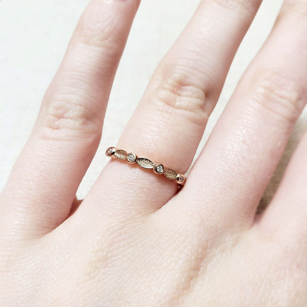 14k rose gold leaf and diamond wedding ring shown on a hand