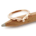 14k rose gold leaf wedding ring with diamond, displayed on a wooden pencil
