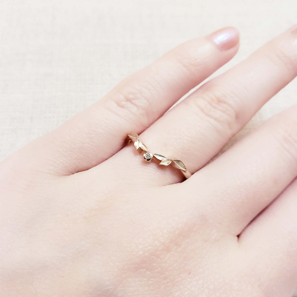 14k rose gold leafy wedding ring with diamond shown on a hand