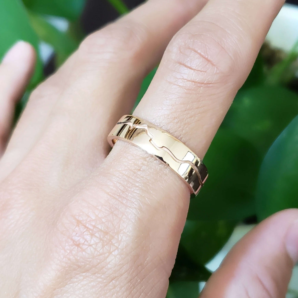 14k rose gold mountain range wedding ring worn on a hand, high polished finish