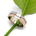 14k white and rose gold mountain range wedding ring resting on a green leaf