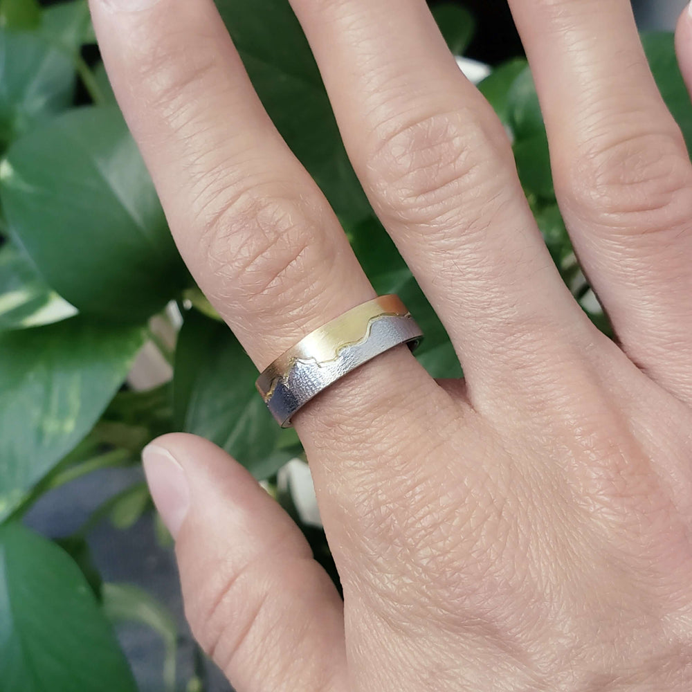 14k white and rose gold mountain range wedding ring shown on hand