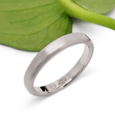 14k white gold brushed wedding ring displayed with a green leaf background