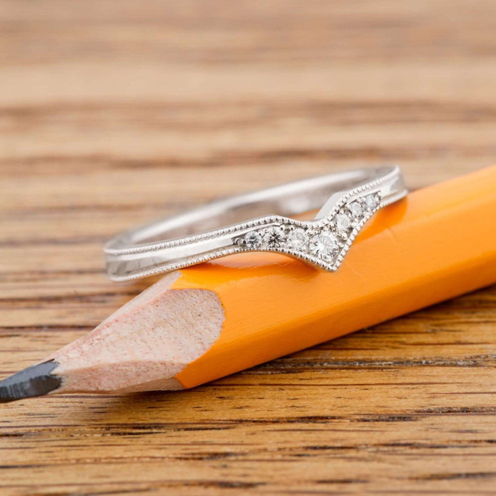14k white gold chevron diamond wedding ring resting on a yellow pencil