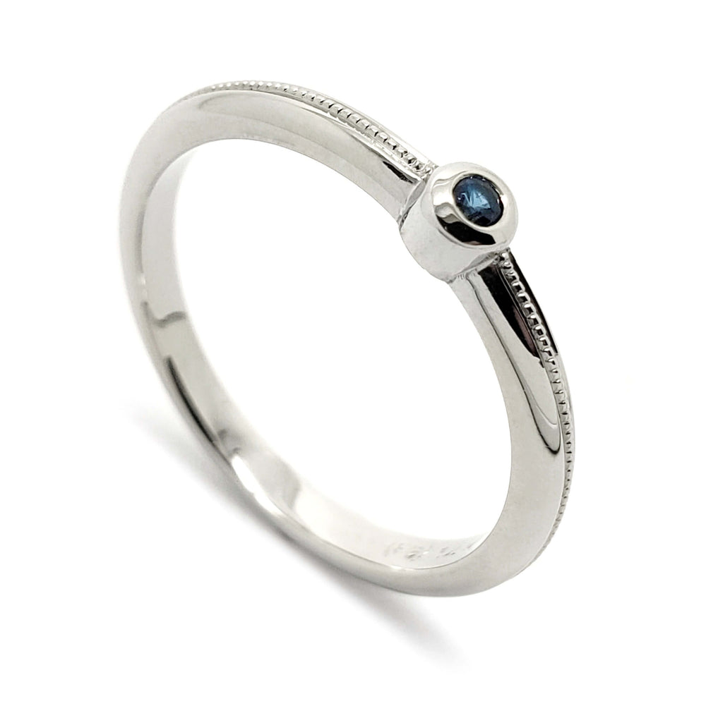 14k white gold stacking ring with bezel-set blue sapphire and millgrain detail