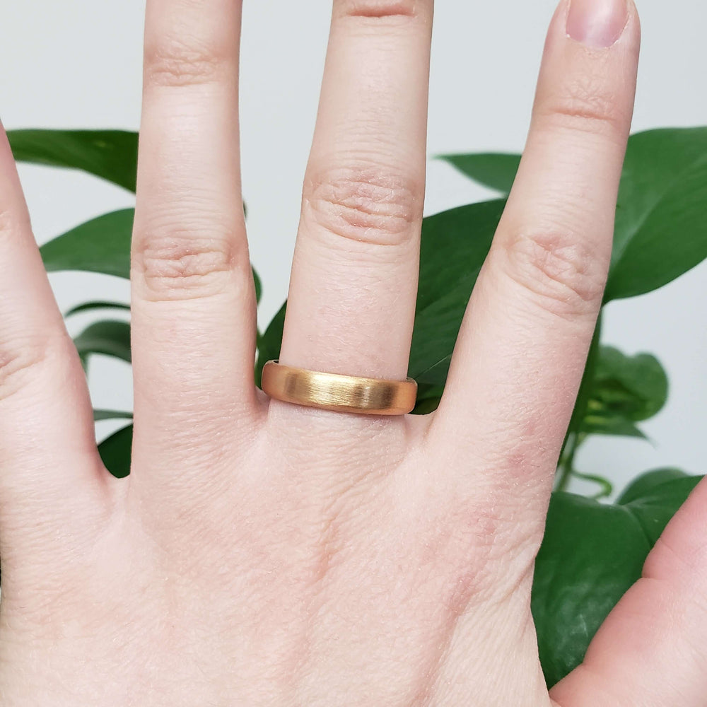 14k yellow gold brushed wedding ring worn on a hand