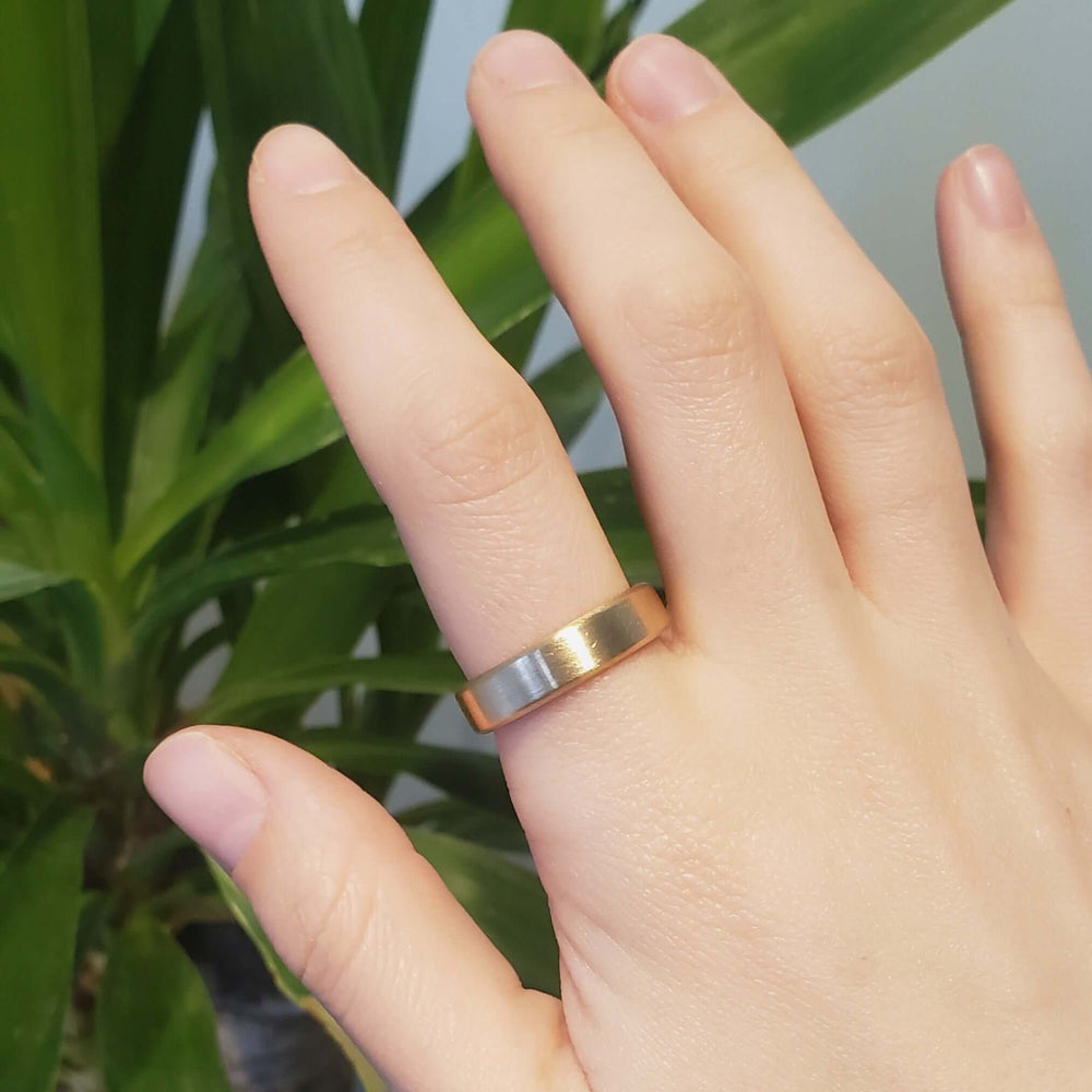 14k yellow gold flat wedding ring with brushed finish shown on hand