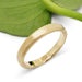 14k yellow gold flat wedding ring with brushed texture beside a green leaf