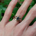 14k yellow gold leaf diamond wedding ring stacked with multiple bands and blue emerald-cut gemstone on hand