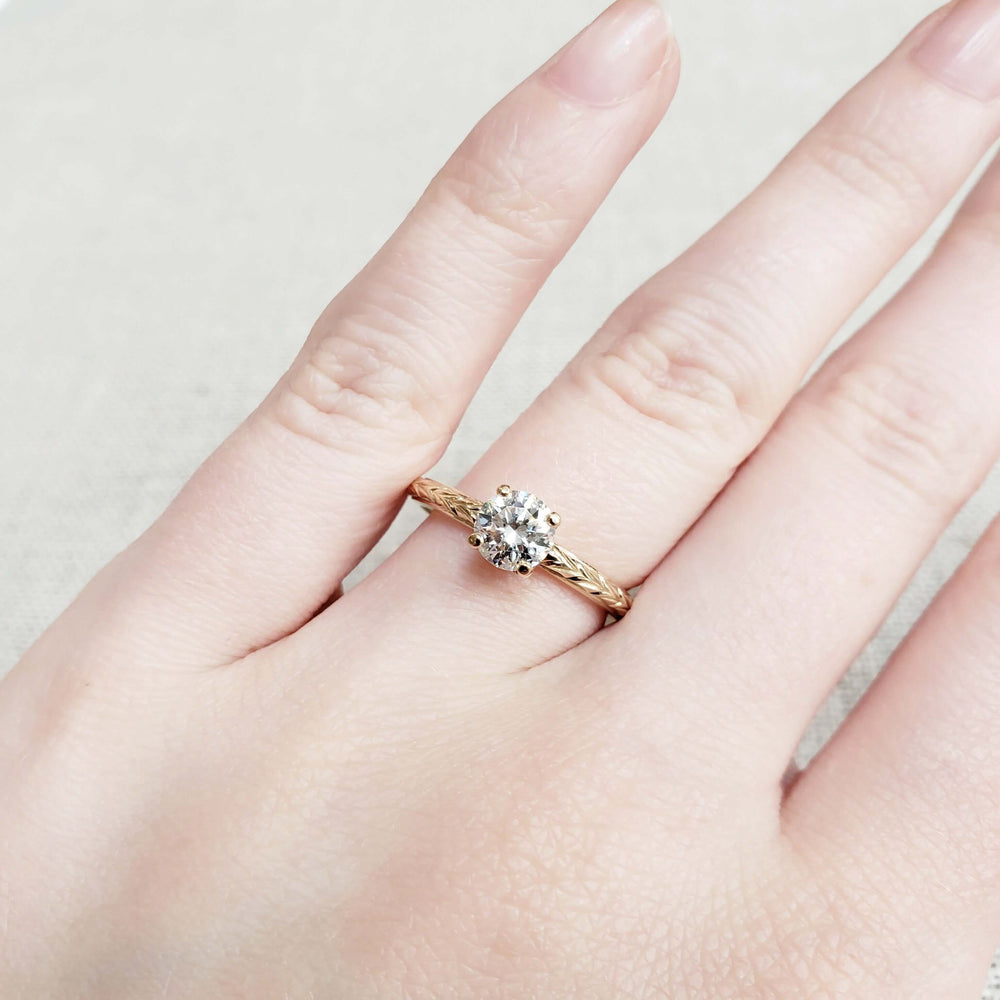 14k yellow gold moissanite engagement ring with engraved band shown on hand