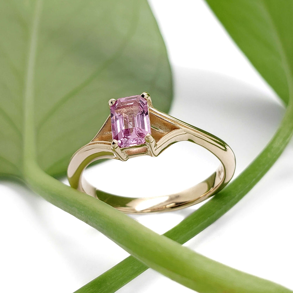 14k yellow gold pink sapphire ring displayed with green leaf background