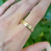 14k yellow gold wedding ring with flush-set diamond, worn on hand