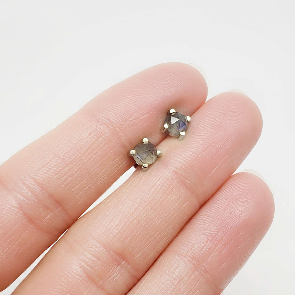Hand holding a pair of 14kt gold labradorite stud earrings