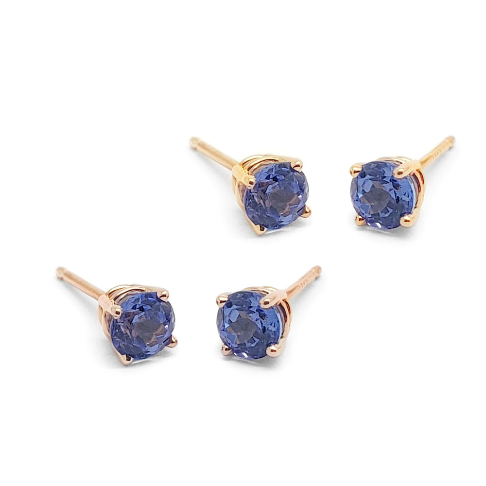 Pair of round tanzanite stud earrings in 14kt gold four-claw settings on white background