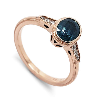 14kt rose gold engagement ring with oval blue Montana sapphire and Canadian diamonds, bezel-set with millgrain detail