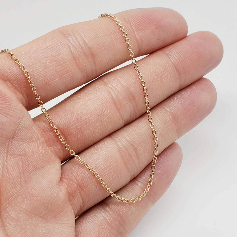 14kt rose gold cable chain necklace draped across a hand