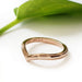 14kt rose gold chevron wedding band with millgrain, shown beside a green leaf