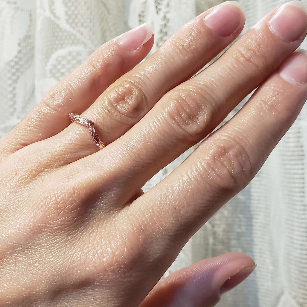 14kt rose gold chevron wedding ring with hand engraving shown on a hand