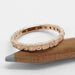 14kt rose gold diamond wedding ring resting on a pencil, showing flush set diamonds