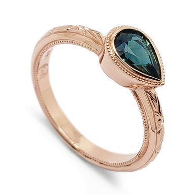 14kt rose gold engagement ring with pear-shaped teal sapphire and hand engraving