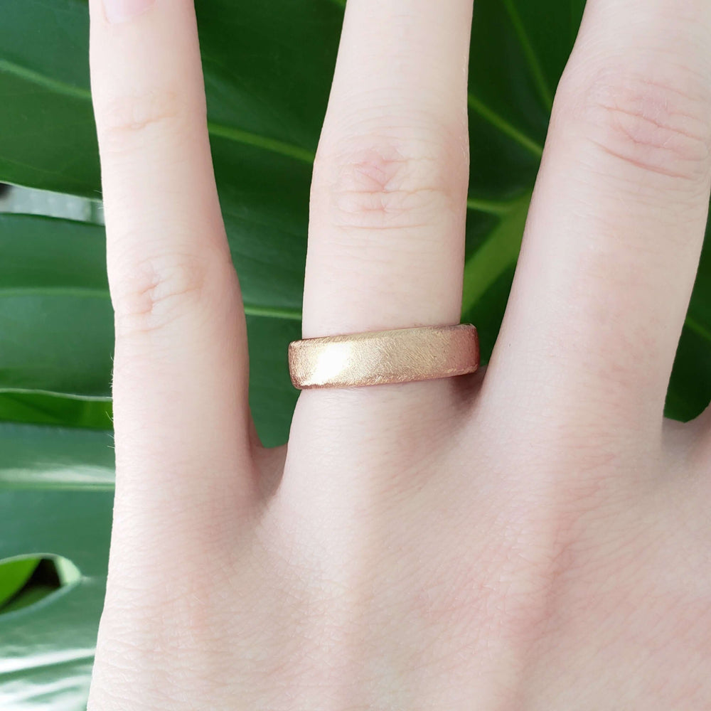 14kt rose gold flat wedding band with saw blade finish shown on a hand