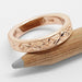 14kt rose gold floral engraved wedding ring displayed on a wooden pencil