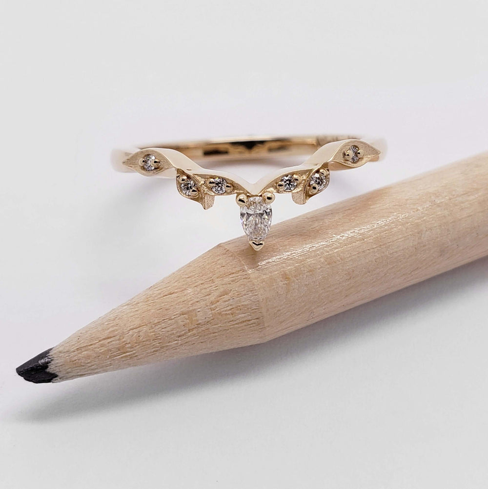 14kt rose gold leafy wedding ring with pear cut diamond, displayed on a pencil