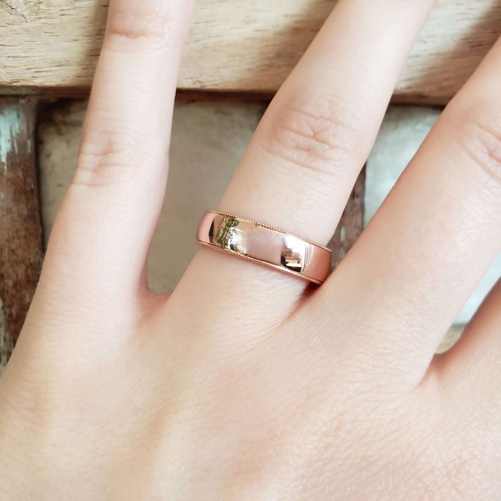 14kt rose gold millgrain wedding ring shown on a hand