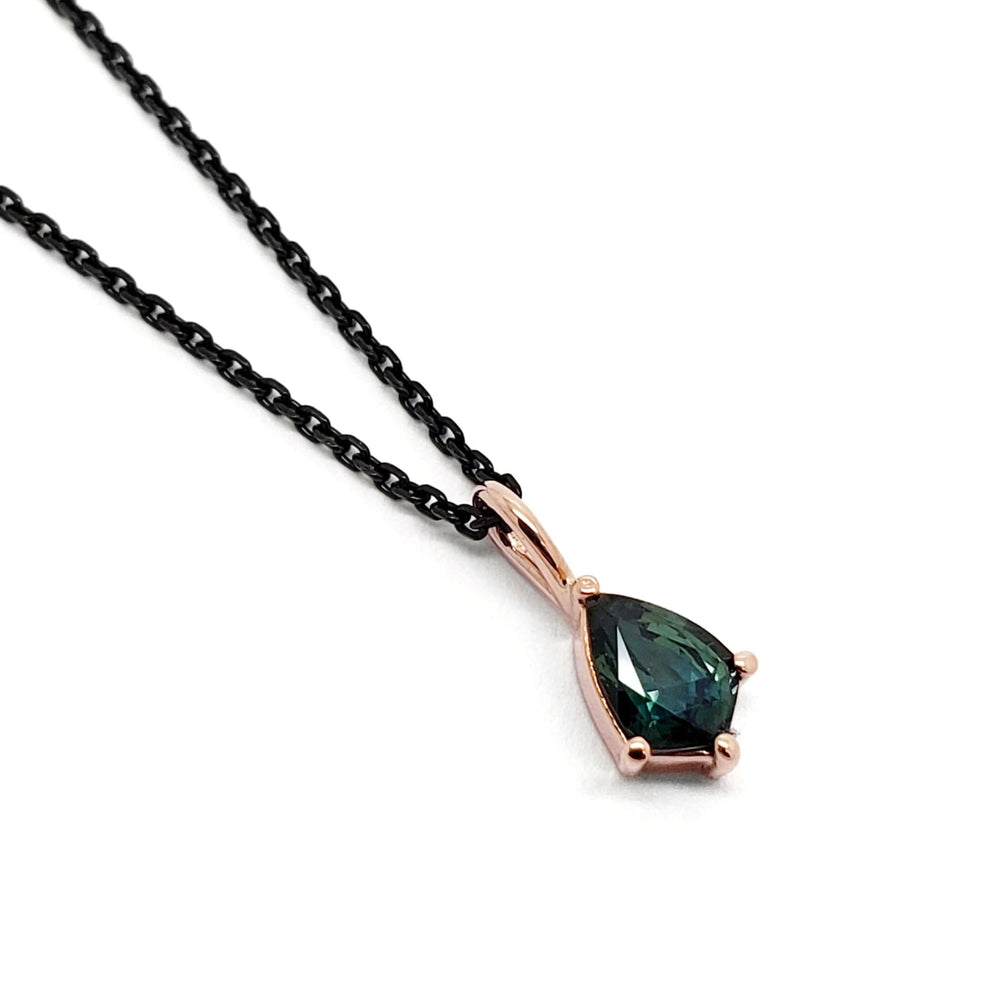 14kt rose gold pendant with shield-cut green sapphire on a black chain, white background