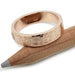 14kt rose gold textured wedding band resting on a pencil, showing artisan detail