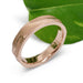 14kt rose gold textured wedding ring beside a green leaf