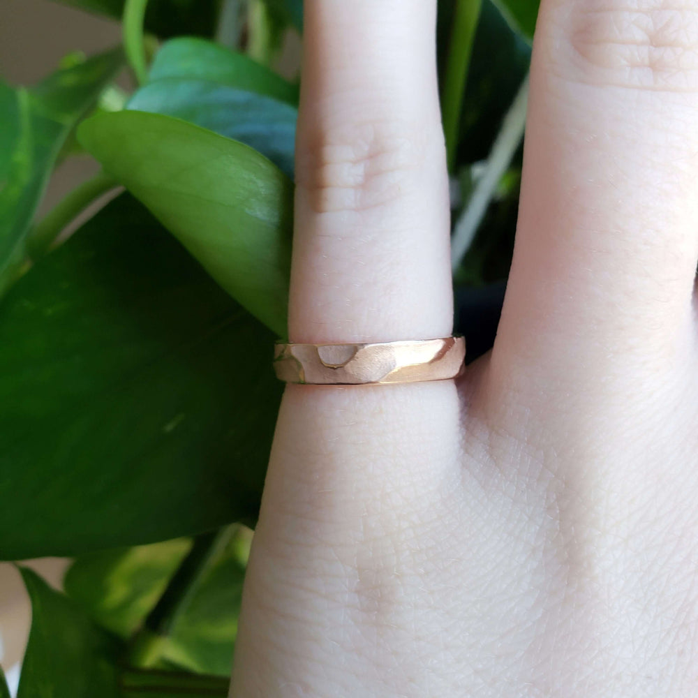 Hand wearing a 14kt rose gold topography textured wedding ring