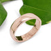 14kt rose gold wedding band with a polished finish, shown beside green leaves