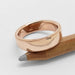 14kt rose gold wedding band with millgrain edge resting on a pencil