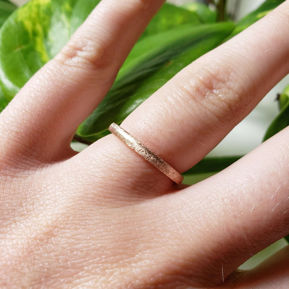 14kt rose gold wedding band with saw blade texture shown on hand
