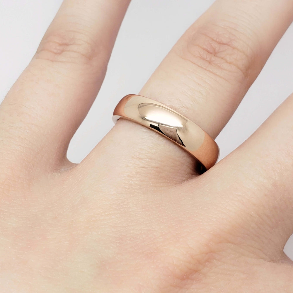 14kt rose gold wedding ring with low dome profile shown on a hand
