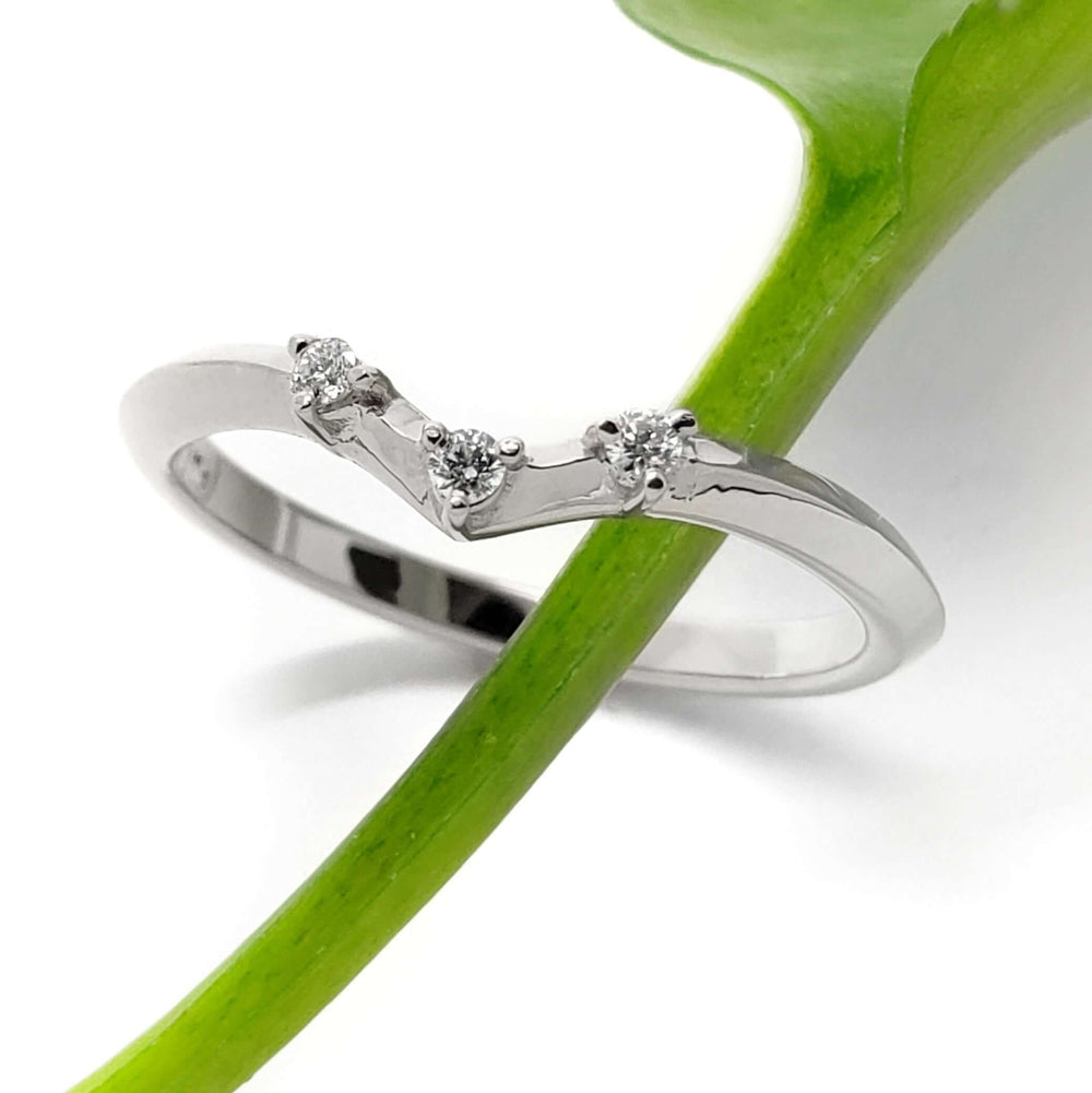 14kt white gold chevron diamond ring with three diamonds, shown with green leaf