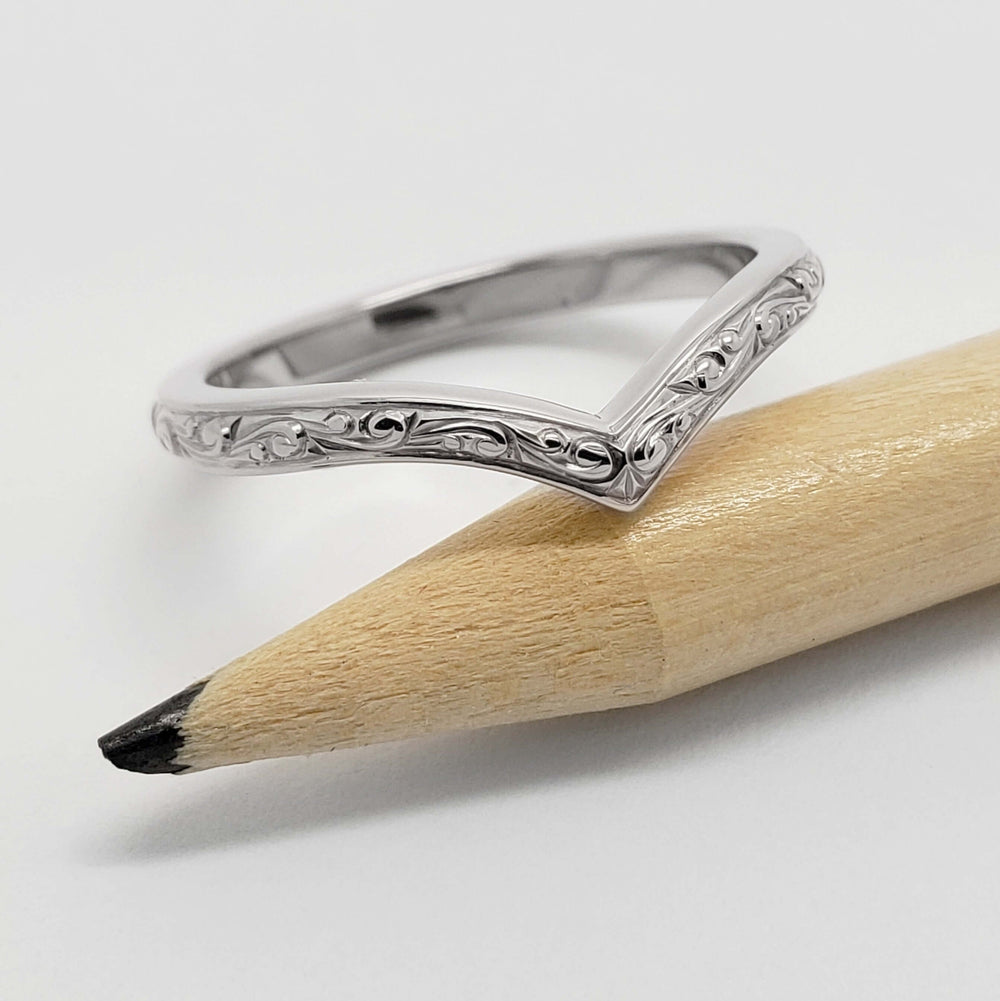 14kt white gold chevron wedding ring with engraved detail, displayed on a pencil