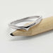 14kt white gold chevron wedding ring with millgrain, resting on a pencil