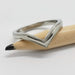 14kt white gold chevron wedding ring with millgrain, resting on a pencil