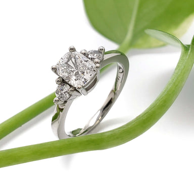14kt white gold cushion cut lab diamond ring with side stones, shown with green plant