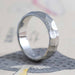 14kt white gold custom carved wedding ring with rough faceted texture, angled on paper