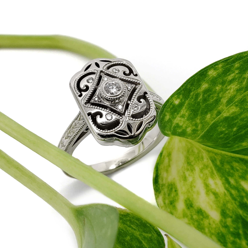 14kt white gold diamond engagement ring with Edwardian engraved design, styled with green leaves