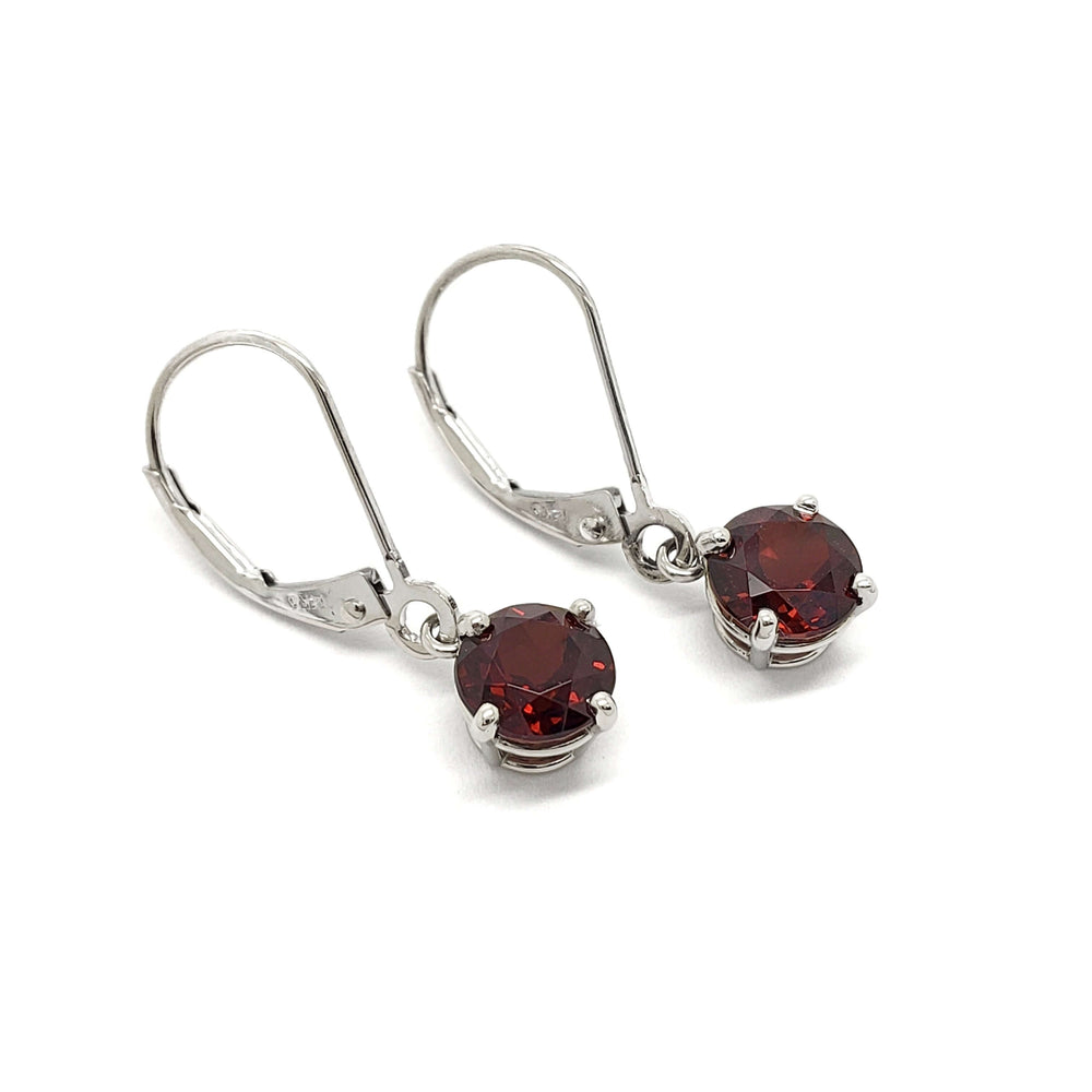 Pair of 14kt white gold drop earrings with round red garnets on white background