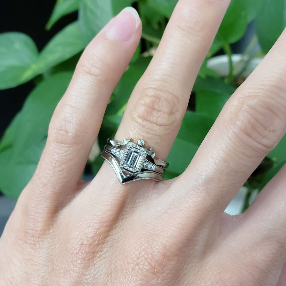 14kt white gold emerald cut lab diamond engagement ring stacked with two wedding bands, on hand
