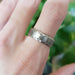 14kt white gold engraved wedding ring with brushed finish shown on a hand