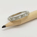 14kt white gold engraved wedding ring with diamonds, resting on a pencil